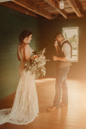 A sunlit wedding moment captured in warm tones inside a rustic wooden room.