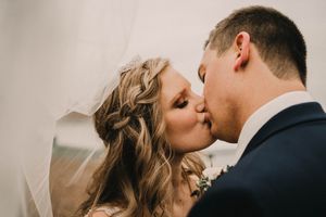 An intimate wedding portrait capturing a romantic kiss with delicate veil details.