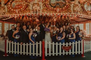 Wedding party poses together in front of vintage carnival carousel.