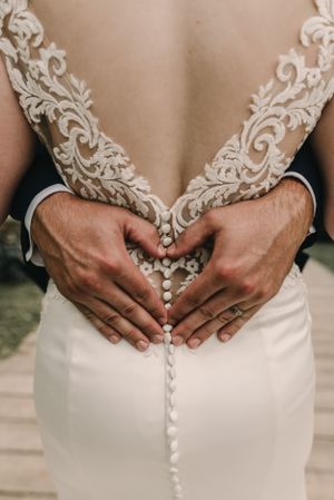 Close-up of intricate lace detailing and buttons on the back of a white wedding dress.