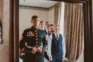 A military service member and groomsmen getting ready in a hotel room before the ceremony.