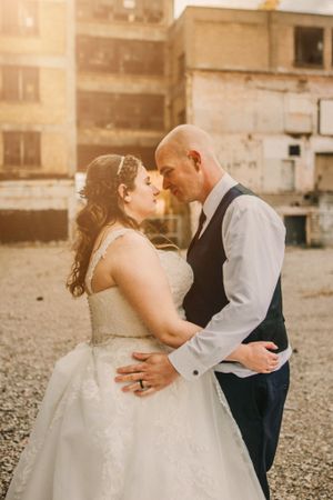 A tender moment between newlyweds during golden hour against an industrial backdrop.
