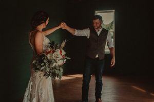 Couple shares their first dance in a dimly lit venue with romantic lighting.