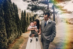 A couple standing outdoors among evergreen trees during a sunset wedding photo.