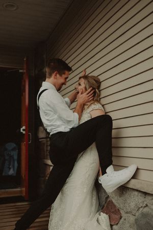 A playful wedding moment captured against a white wooden wall.