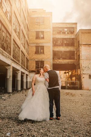 A wedding photo shoot in front of an industrial building at golden hour.