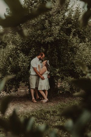 A romantic couple embraces in a lush garden setting with dreamy bokeh effect in vintage style.