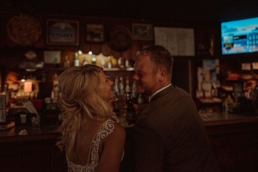 A romantic moment captured at a dimly lit bar with wood paneling and vintage decor.