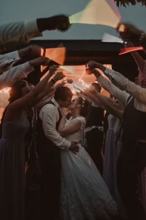 Wedding couple shares first dance under guests holding sparklers at twilight.