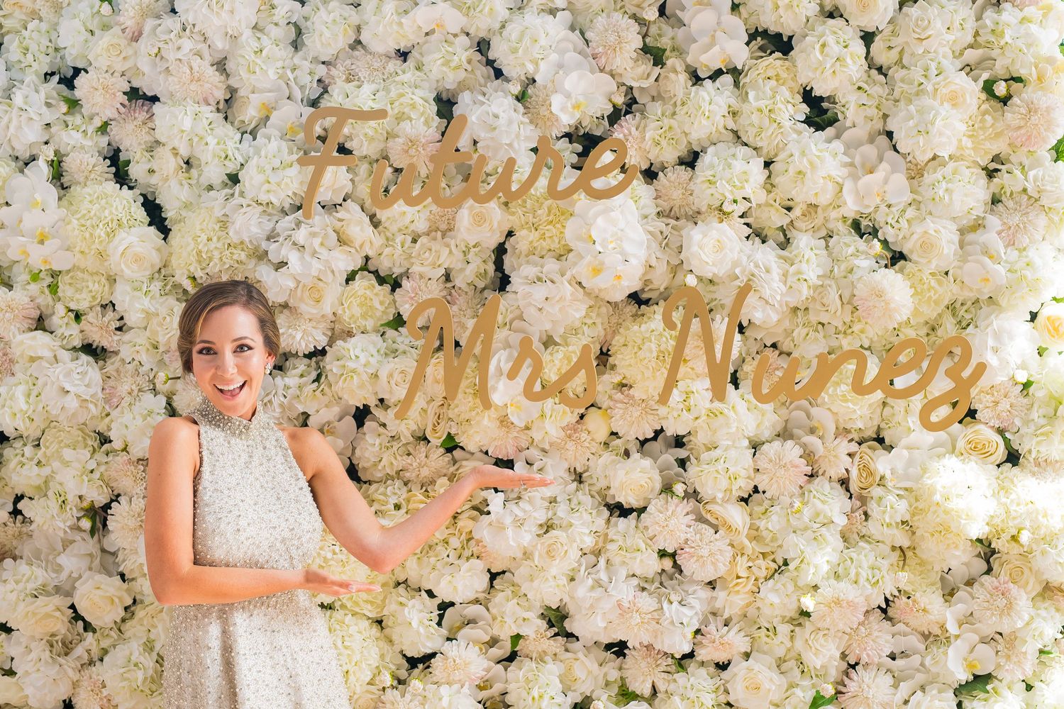 Elegant white flower wall installation with gold lettering creates a stunning photo backdrop.
