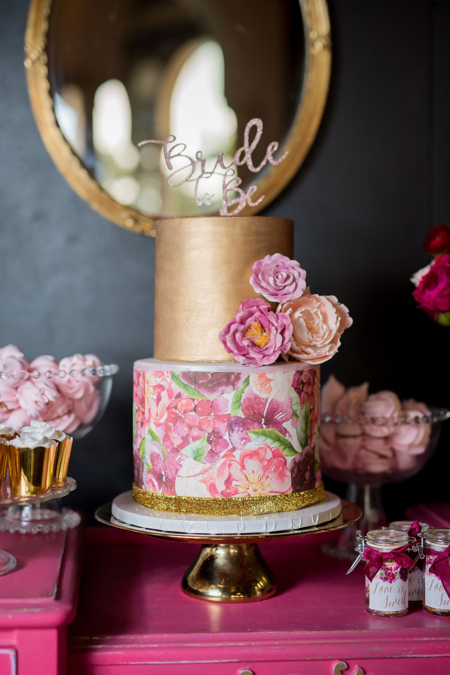 Elegant wedding cake with gold tier, floral design, and pink roses on a gold cake stand.
