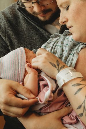 Close-up of new parents tenderly cradling their newborn baby.
