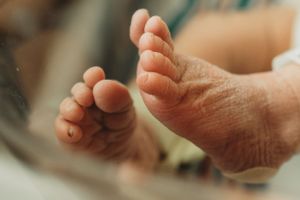 Close up of tiny newborn baby feet against a soft background.