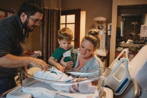 People gathered around hospital bed with young child reviewing documents.