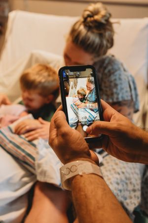 Someone taking a photo on their phone of a family moment in a hospital room.