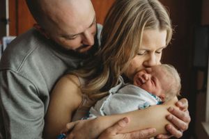Parents sharing an intimate moment with their newborn baby wrapped in soft blankets.