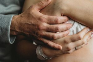 Close-up of gentle hands touching and comforting a newborn baby.