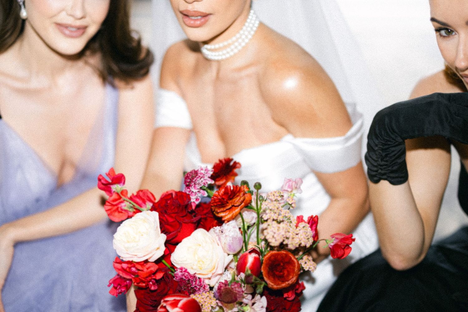 Wedding party holding vibrant red and white floral bouquets.