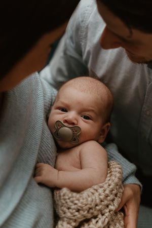 Sweet baby wrapped in knit blanket during intimate portrait session.