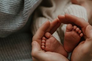 Close-up of tiny baby feet being held by caring hands.