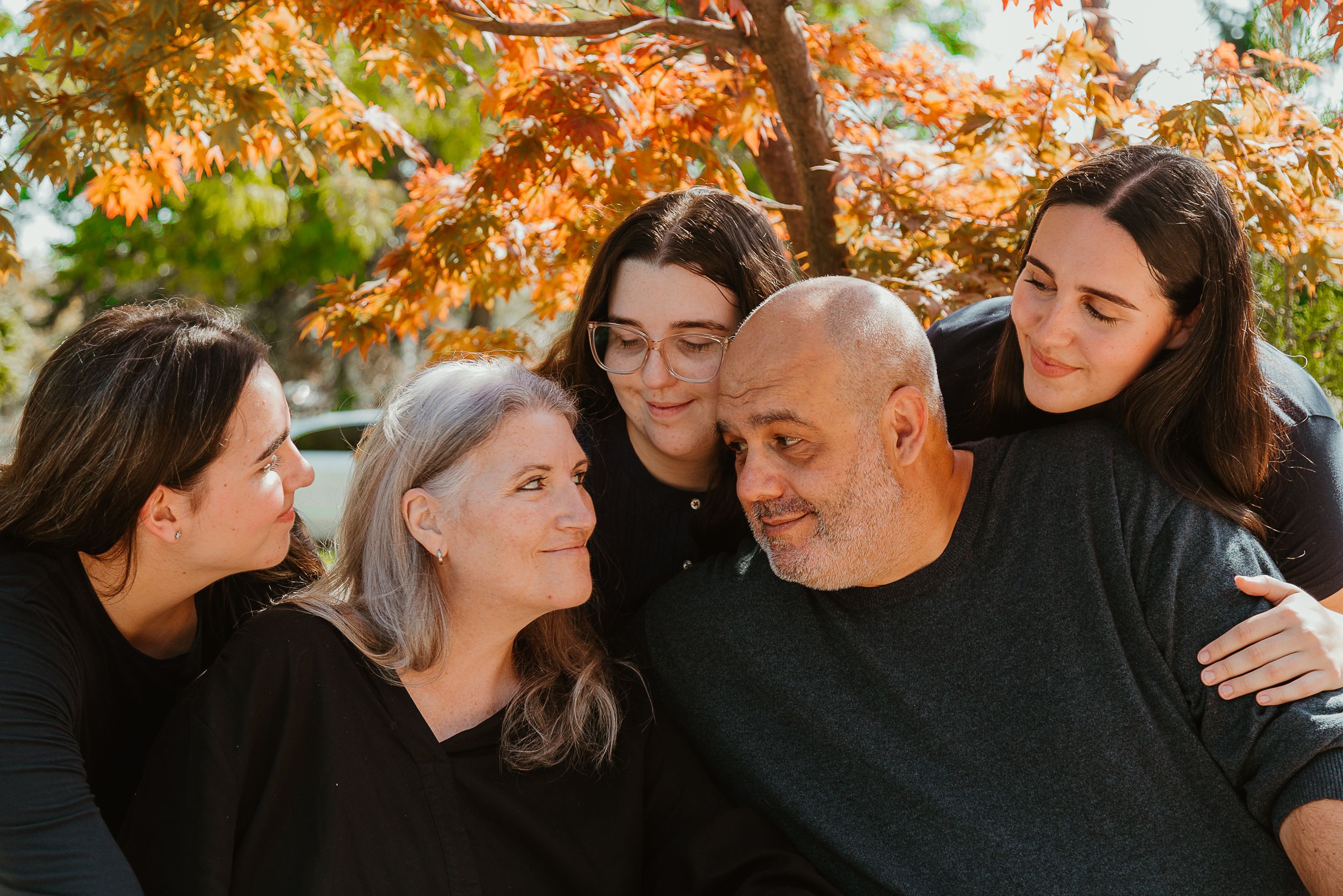 Loving family share intimate moment in an autumn setting surrounded by colourful fall foliage.