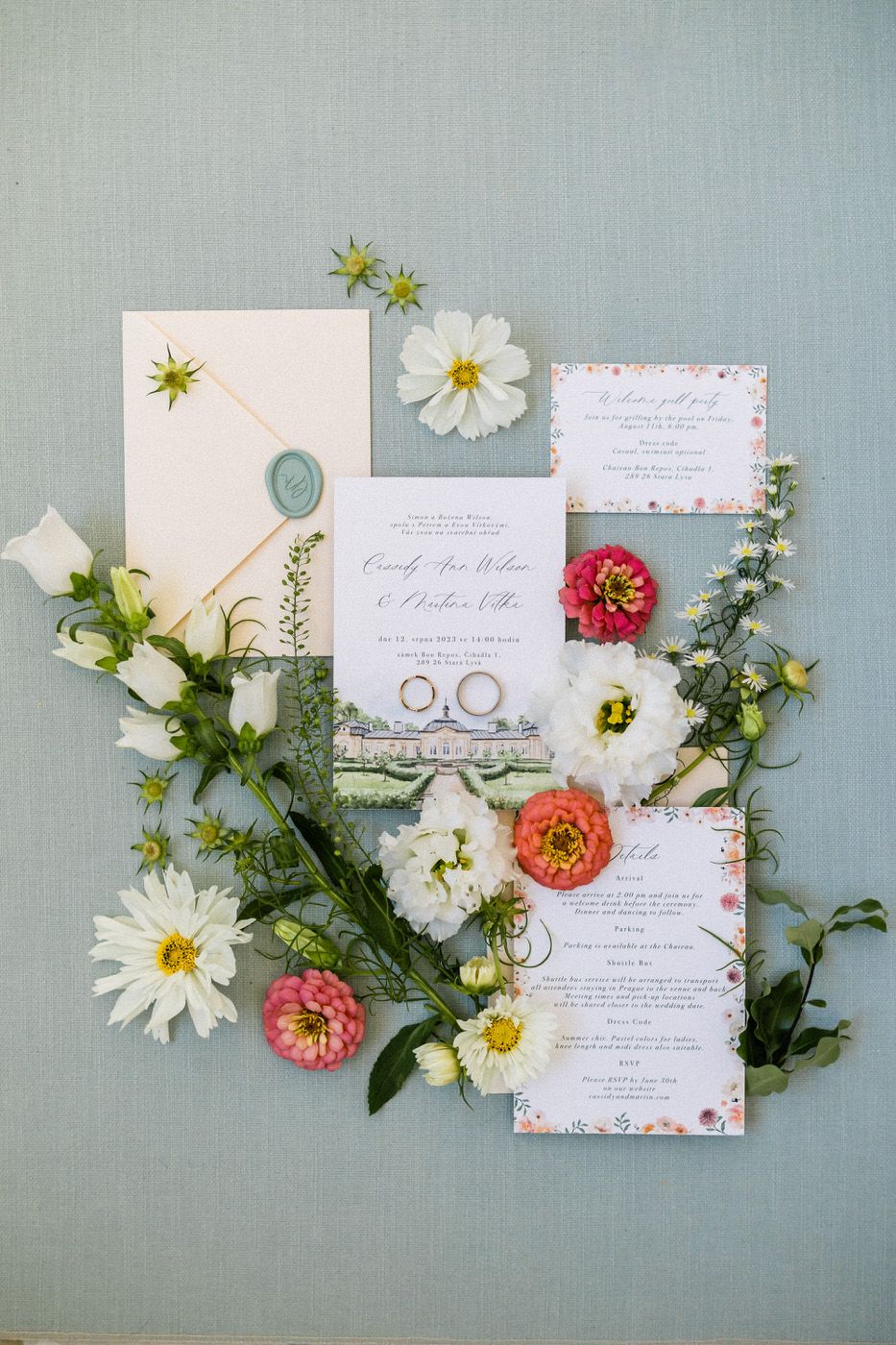 Wedding invitation suite with floral details and rings styled with fresh flowers.
