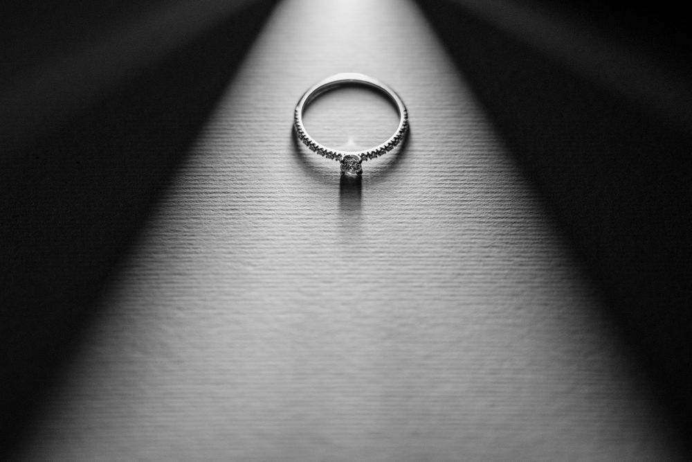A silver engagement ring with a solitaire diamond shown from multiple angles in black and white photos.