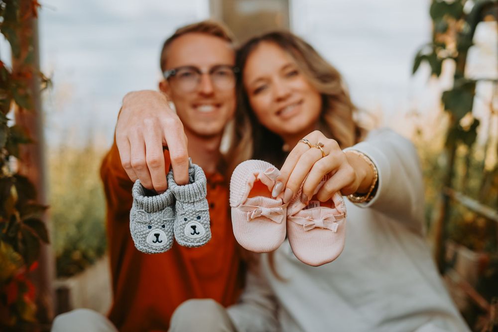 A couple holds up tiny baby shoes to announce their pregnancy.