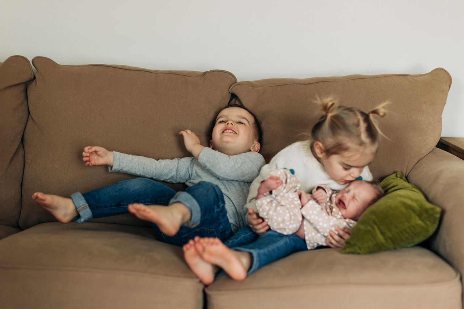 Children relax and play together on a brown sofa.