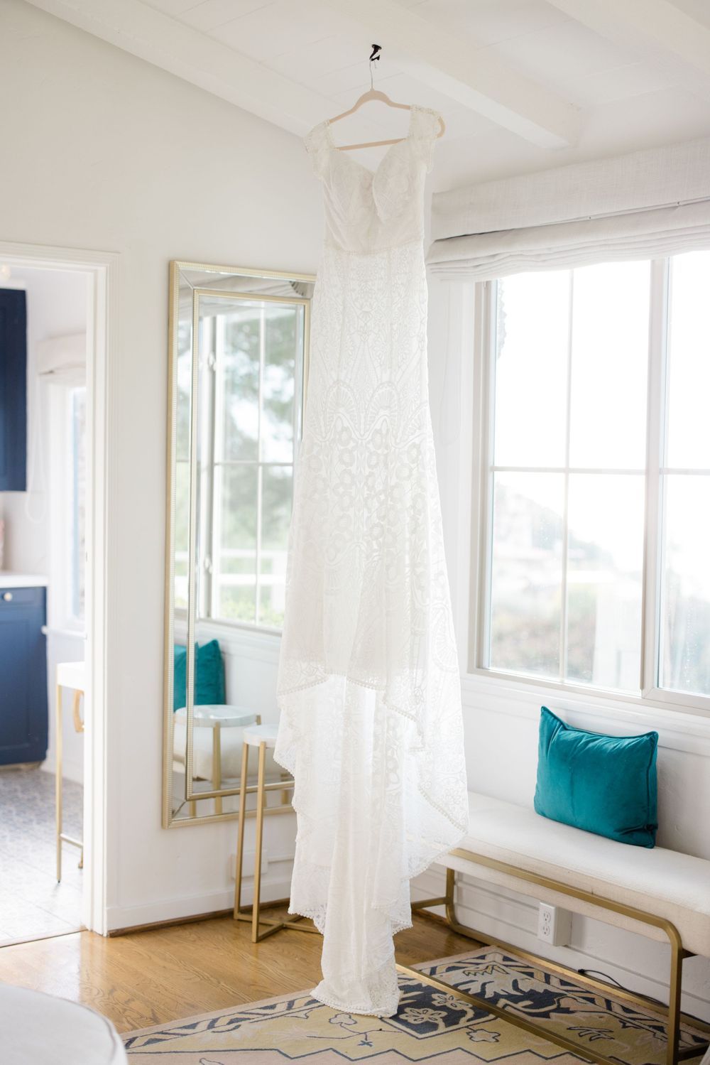 Bright white dressing room with windows, mirrors and teal accent pillows.