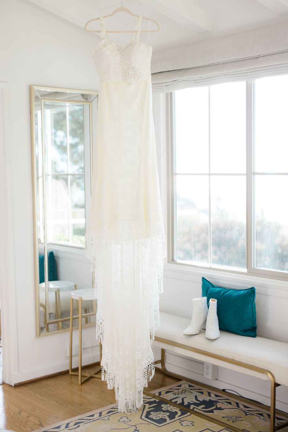 Minimalist white dressing room with teal pillows and natural light from windows.