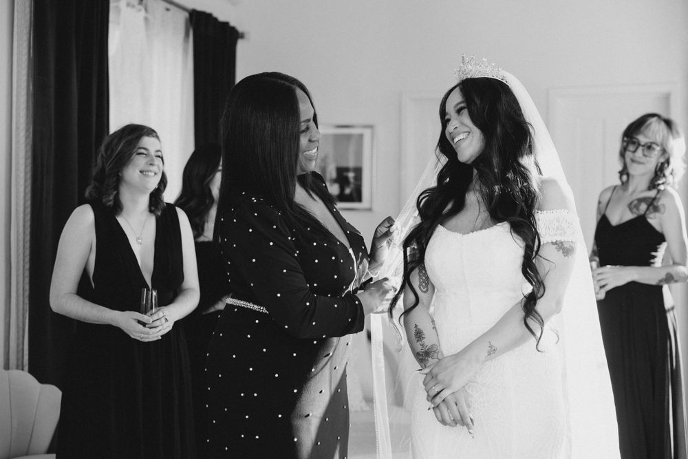 Wedding party getting ready in a bright room wearing black and white attire.