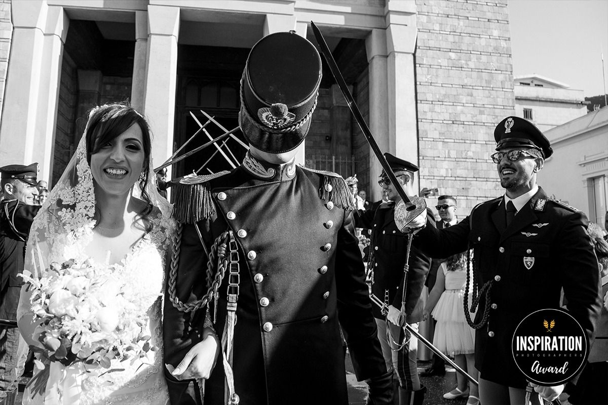 A black and white wedding photo showing a couple and military officer in uniform outside a building.