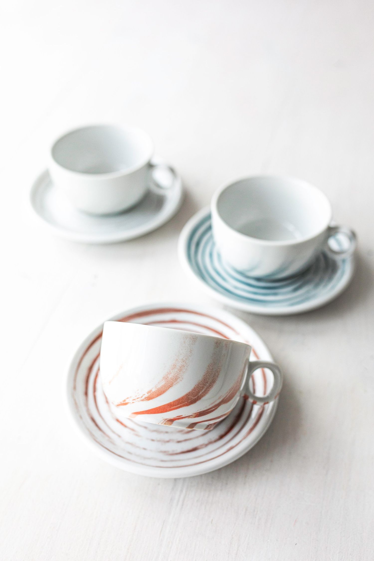 Porcelain plates and cups with digitally printed circular patterns in blue, red, gray and azur.