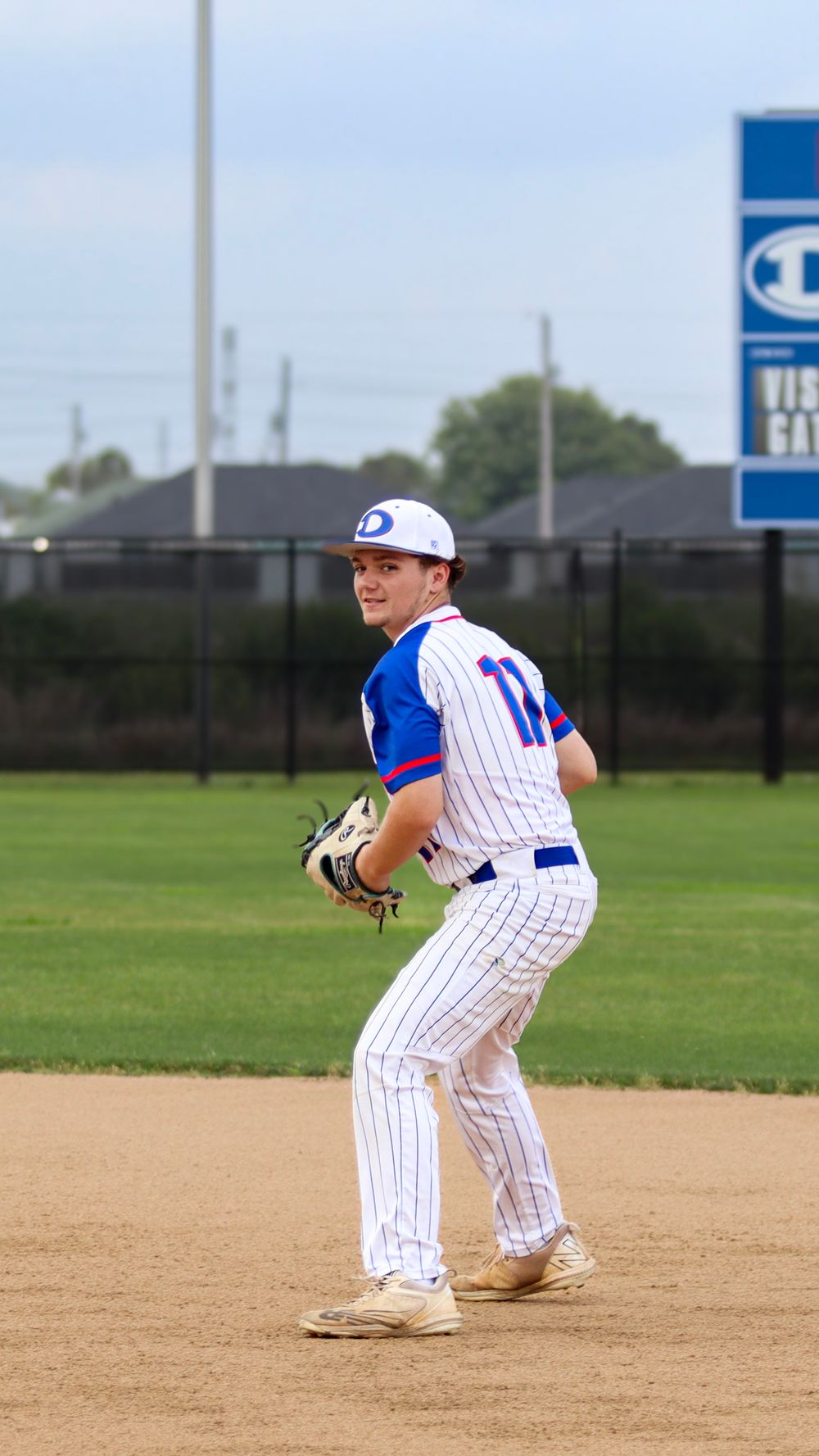 Baseball player in pinstriped uniform demonstrates pitching stance on field.