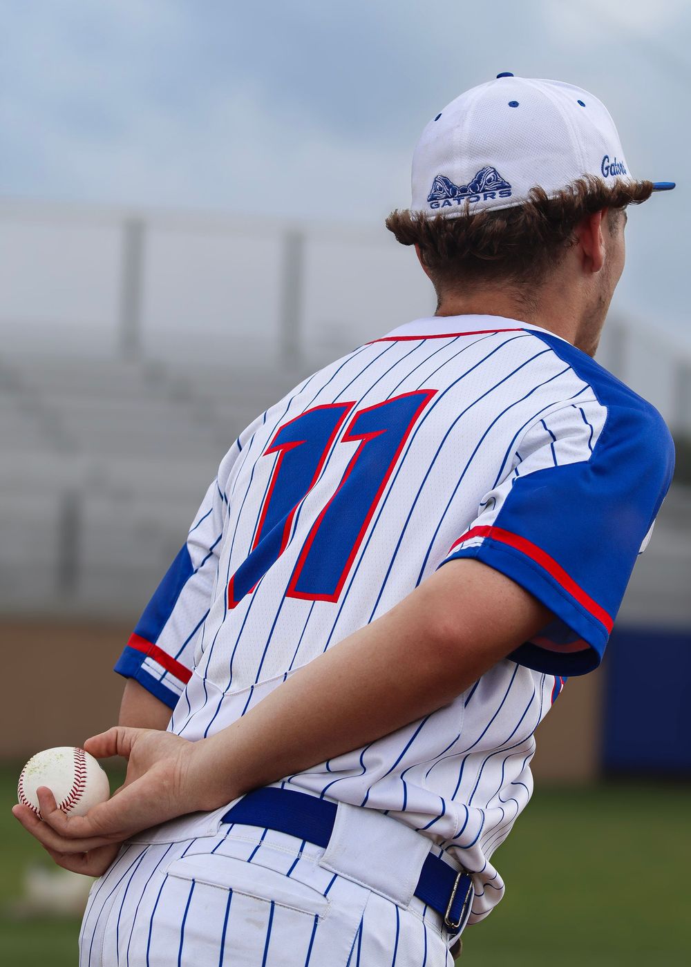 Baseball player in pinstriped uniform holding ball on field.