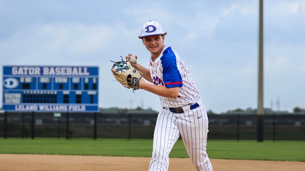 Baseball player in white and blue uniform prepares to throw on baseball field.