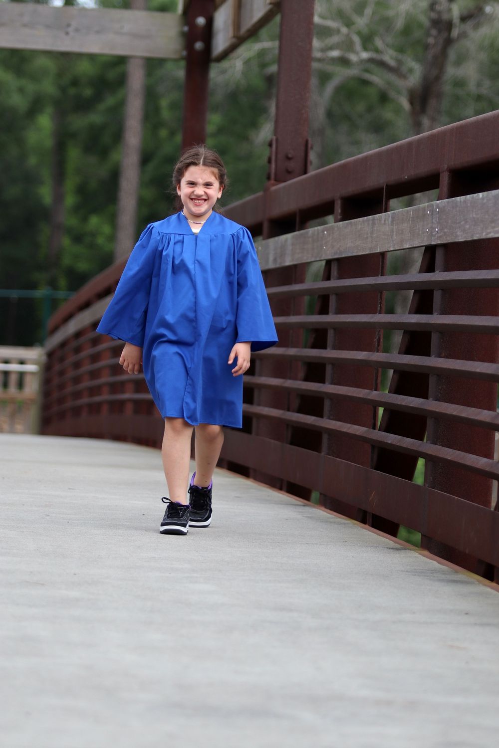 Sequence of photos showing someone in a blue graduation gown walking across a wooden bridge.