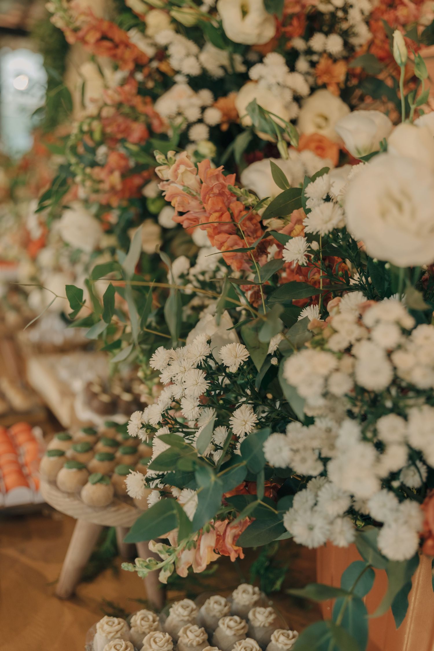 Close-up of coral and white floral wedding arrangements with greenery.