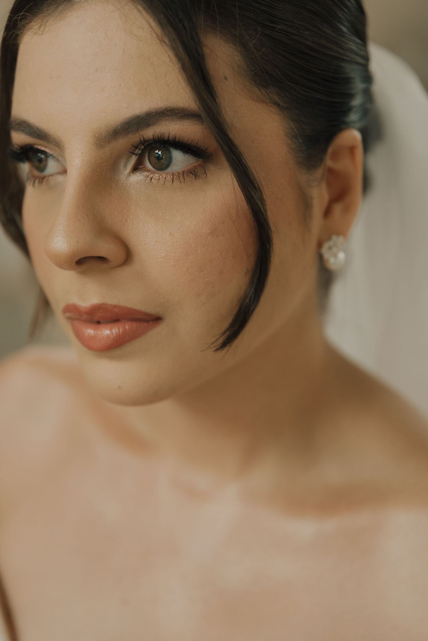Close-up beauty shot of a bride with classic makeup and pearl earrings.