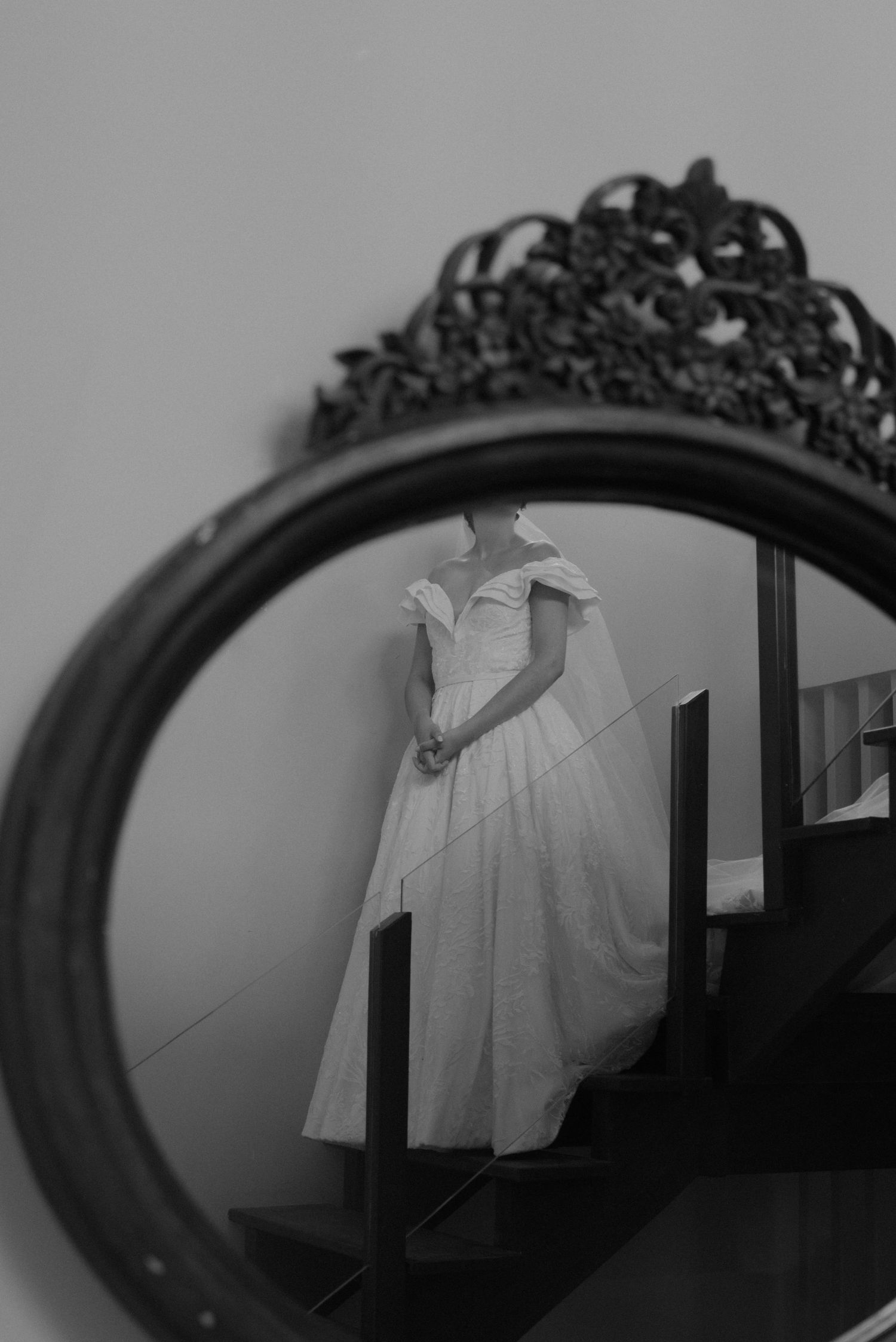 Artistic black and white reflection of a wedding dress in an ornate vintage mirror.