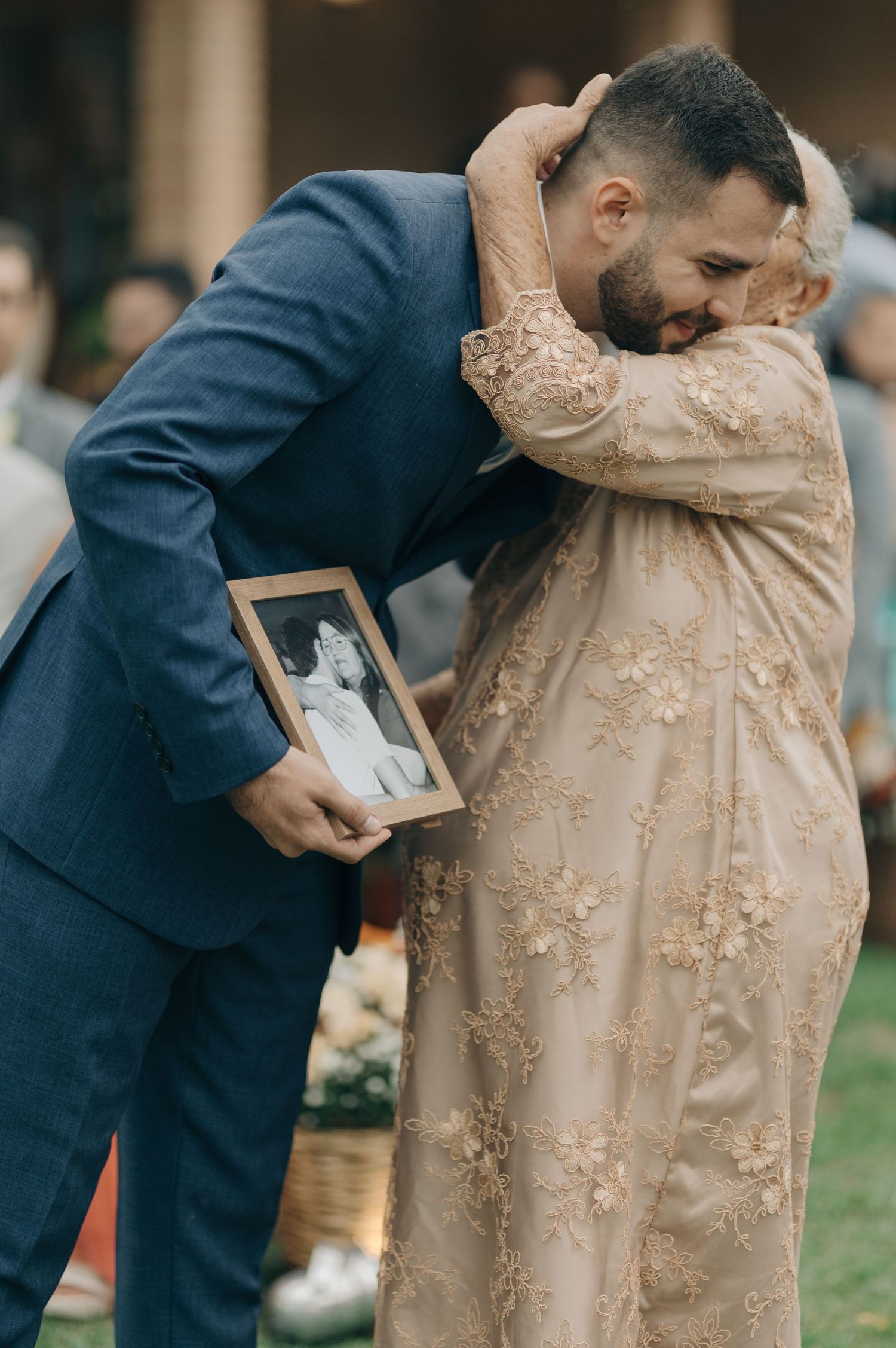 Emotional moment between two people sharing a hug while holding a framed photo.