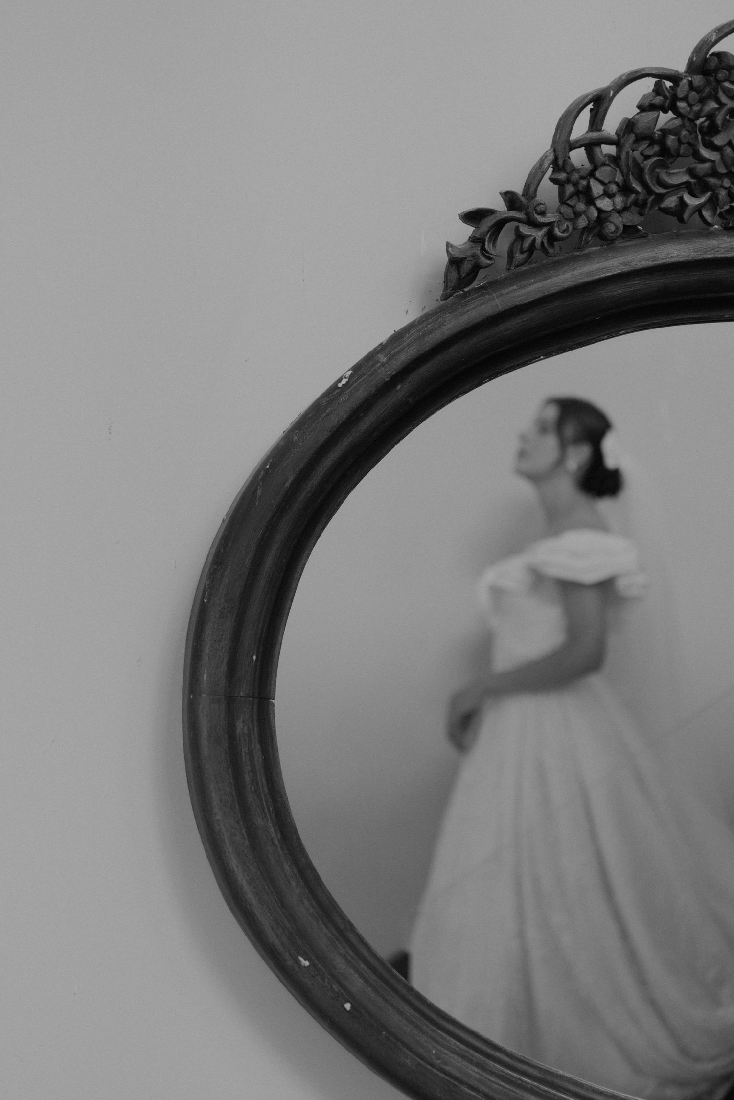 Black and white mirror reflection showing a bride in an off-shoulder ballgown.