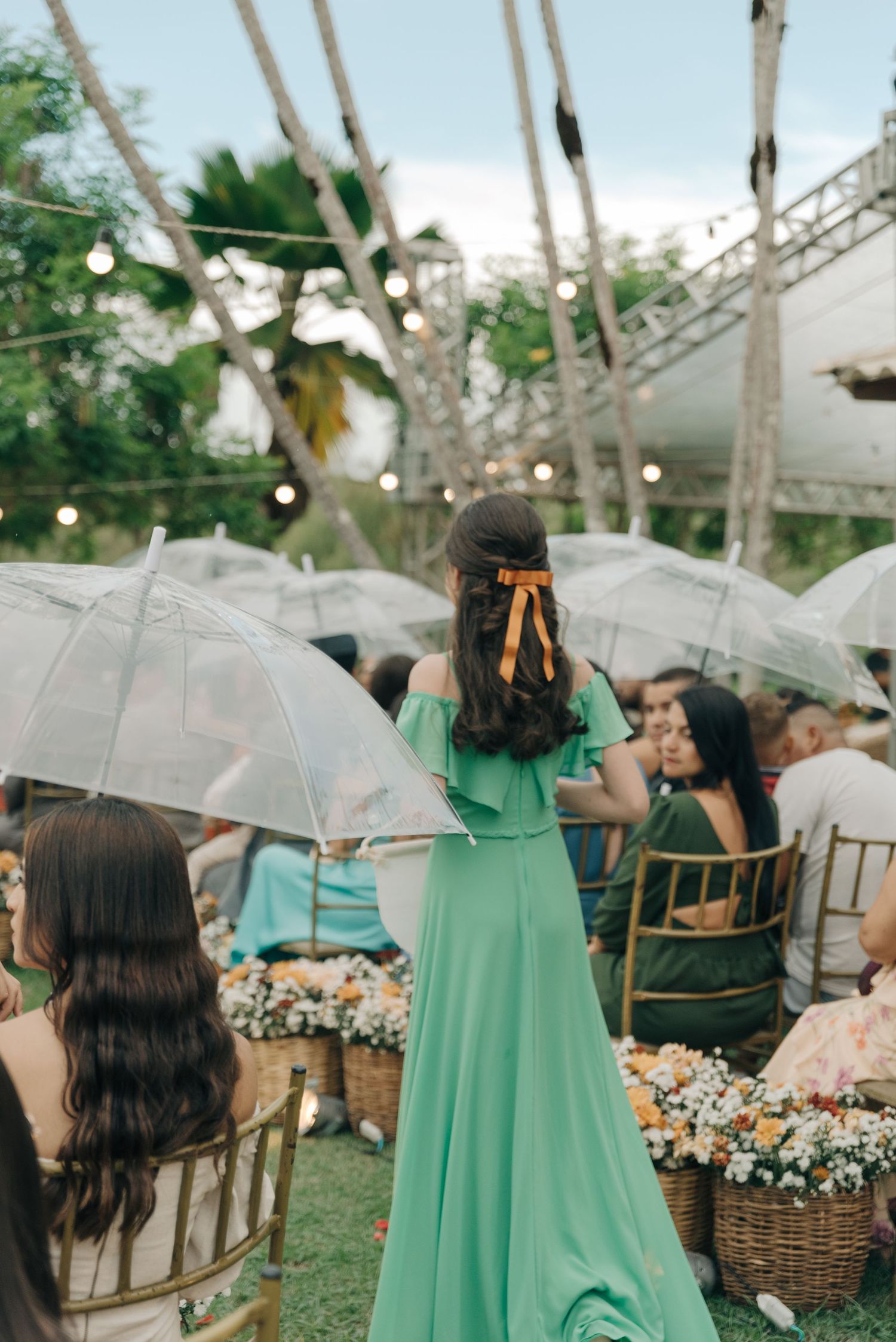 Outdoor wedding reception setup with clear umbrellas and mint green bridesmaid dress.
