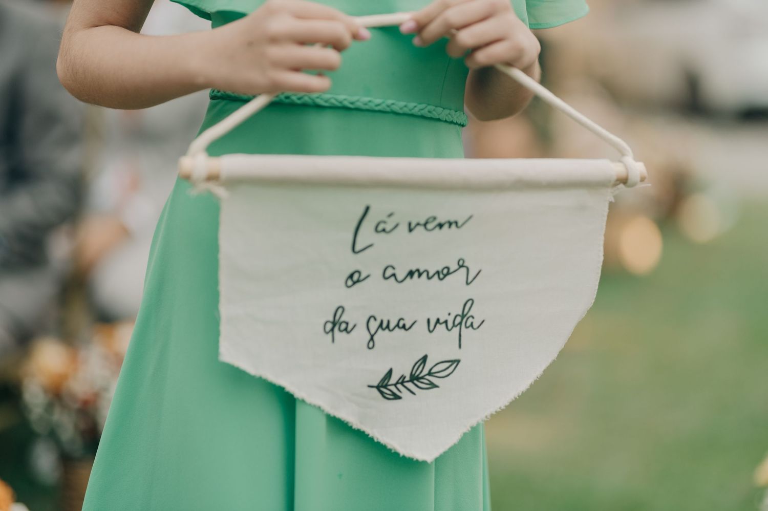 White banner with cursive text and botanical design held against a green dress.