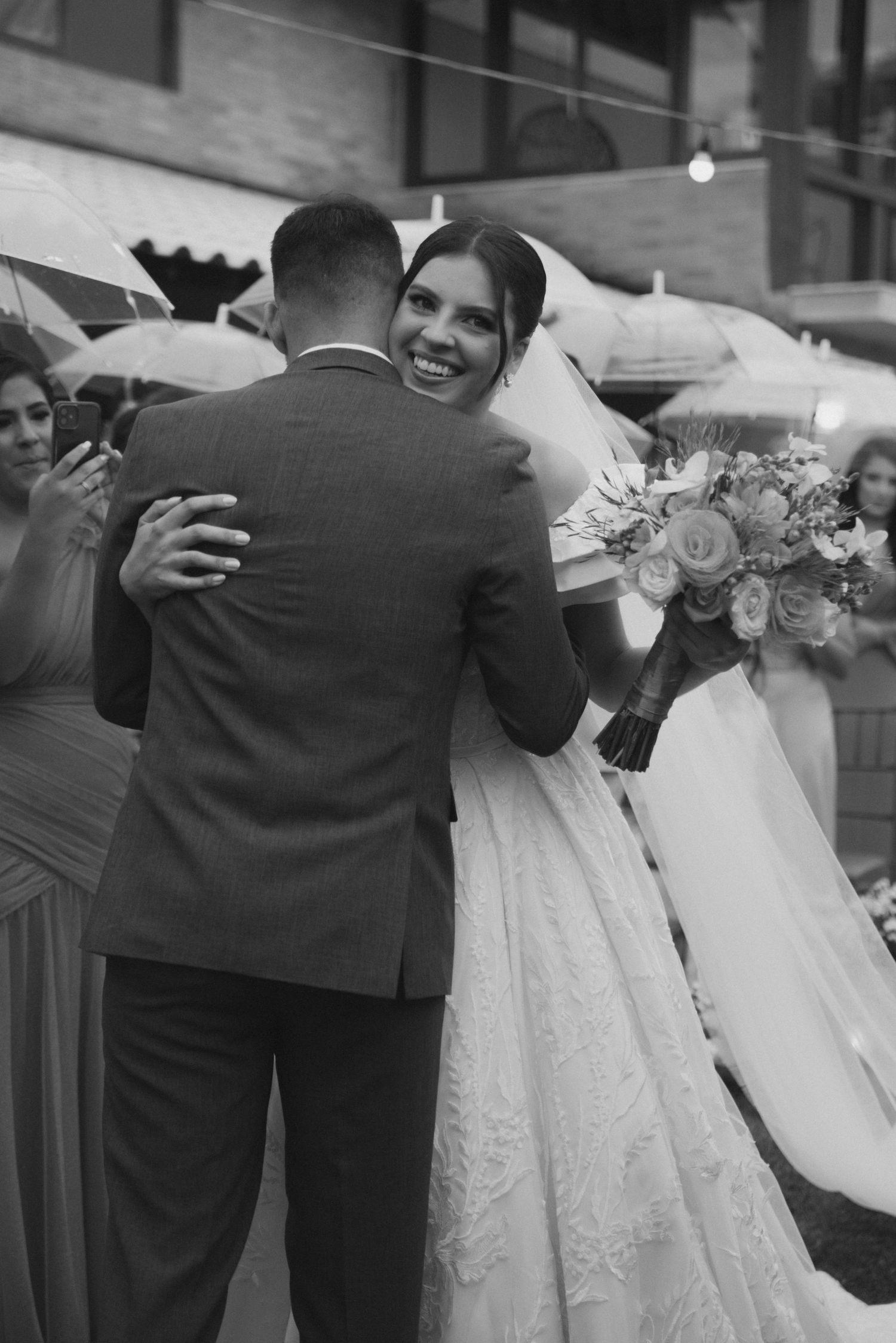 Black and white photo of bride and groom embracing during wedding reception.