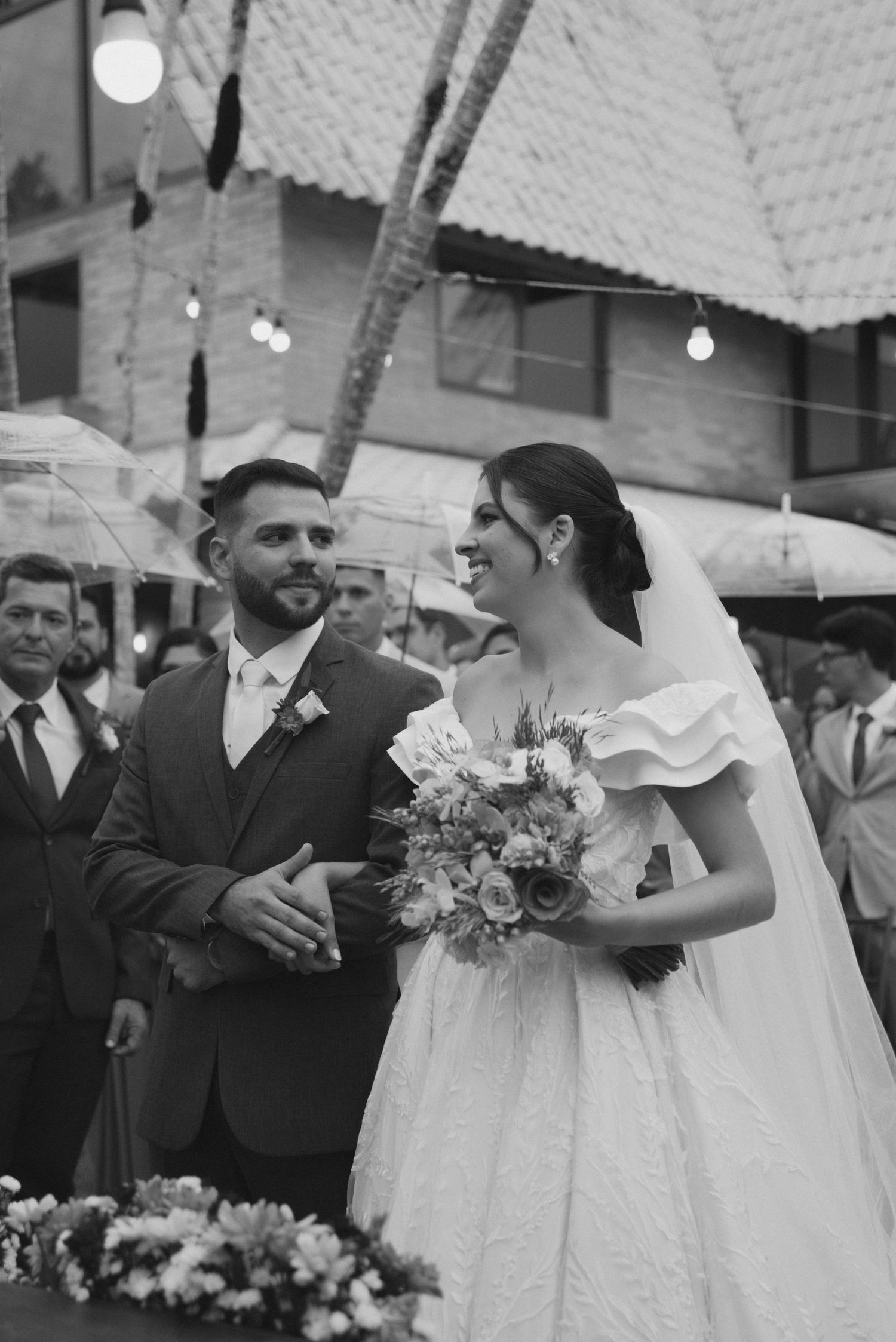 Black and white photo of newlyweds sharing a joyful moment during outdoor ceremony.