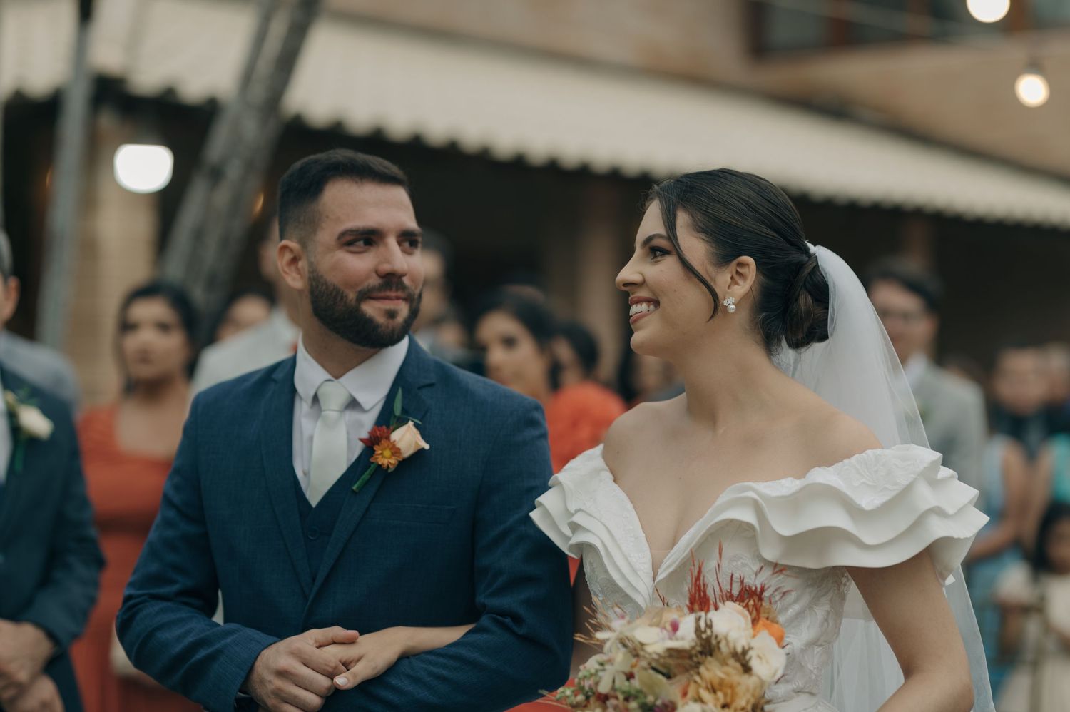 A candid moment during a wedding ceremony with string lights and floral decorations.