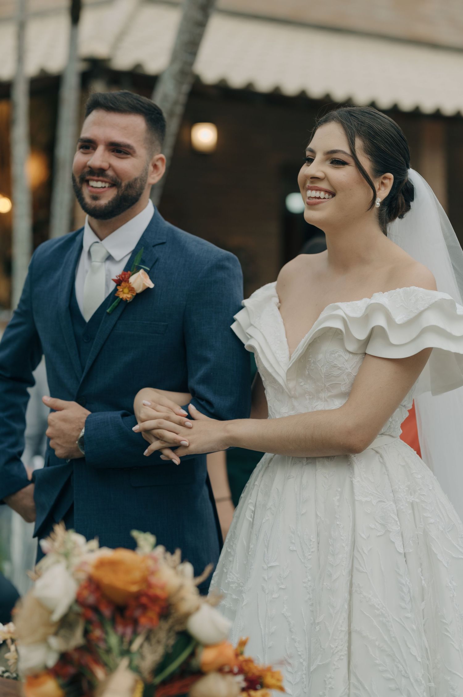 A candid wedding moment showing pure joy during an outdoor celebration with string lights.