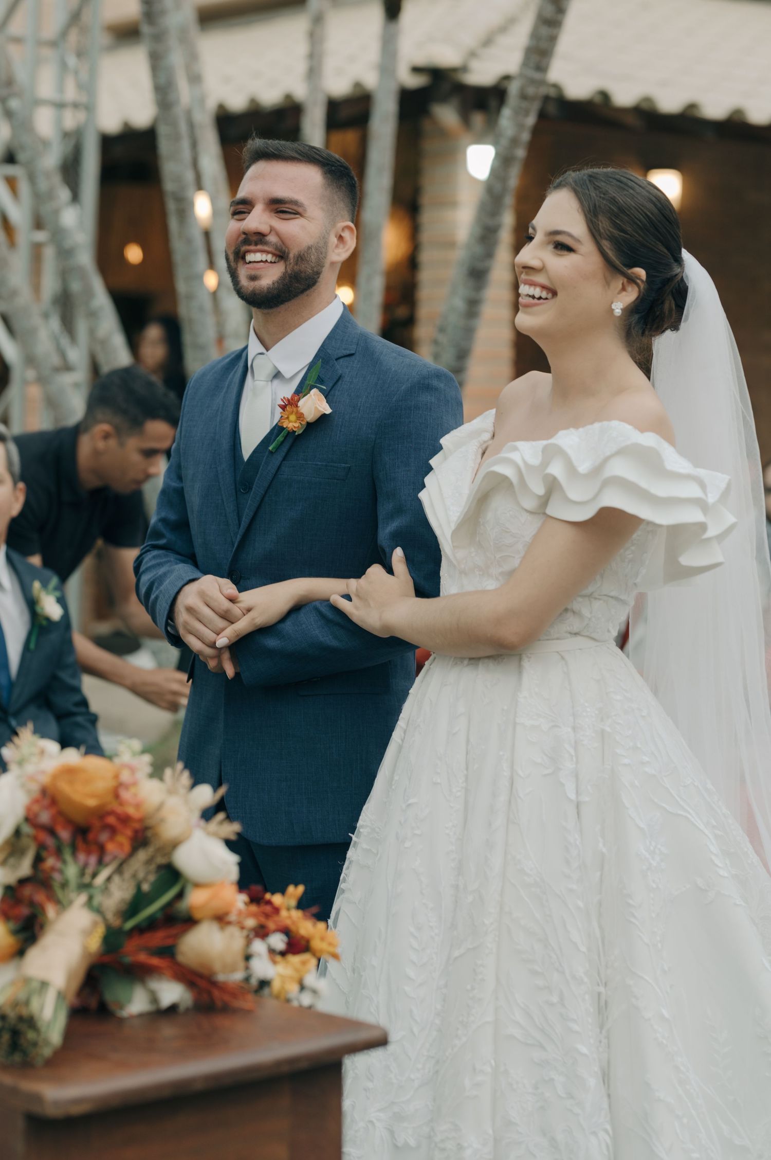 A candid wedding celebration moment with string lights and autumn-toned floral arrangements.